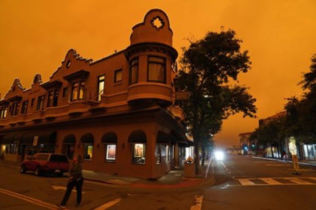 Una mujer cruza una calle frente a un hotel mientras el humo de los incendios forestales oscurece el cielo de la mañana el miércoles 9 de septiembre de 2020, en Sausalito, California (AP Photo/Eric Risberg)